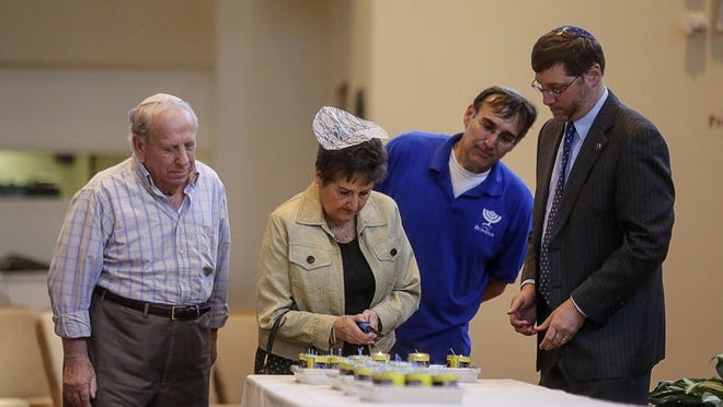 Joseph (left), Mary, and Peter Eckstein light a candle during the 2014 Temple Beth David Yom HaShoah Vigil of Remembrance ceremony on April 27, 2014, in Palm Beach Gardens. From 9:45 a.m. to 9:45 p.m. about 60 people were to venture to the temple to read the names of Holocaust victims from countries all throughout Europe. In addition, during the day the names of Righteous Among the Nations — non-Jews who risked their lives during the Holocaust to save Jews from extermination by the Nazis — would be read as well.