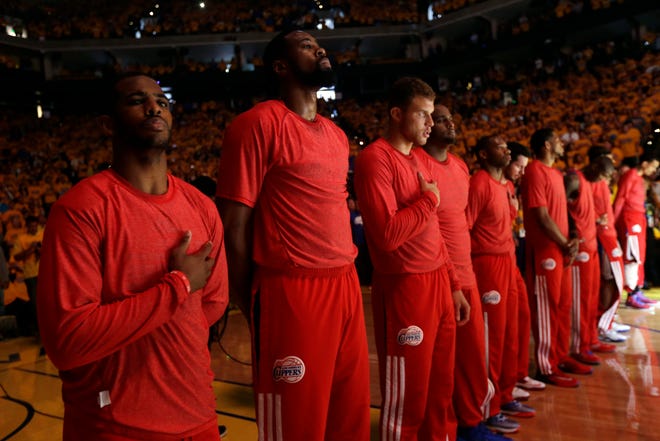 Members of the Los Angeles Clippers wear their red warmup shirts inside out to hide the team's logo Sunday during the national anthem prior to their playoff loss to the Warriors. THE ASSOCIATED PRESS