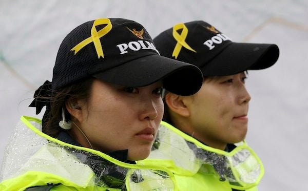 Yellow ribbons as a sign of hope for the safe return of missing passengers of the sunken ferry Sewol are pinned on caps of police woman at a port in Jindo, South Korea, Sunday, April 27, 2014. South Korean Prime Minister Chung Hong-won offered to resign Sunday over the government's handling of a deadly ferry sinking, blaming "deep-rooted evils" and irregularities in a society for a tragedy that has left more than 300 people dead or missing and led to widespread shame, fury and finger-pointing.THE ASSOCIATED PRESS
