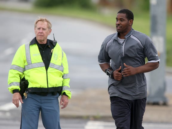 A Cobb County Police officer, left, escorts a FedEx employee as he crosses McCollum Parkway leaving the blocked off area after an early morning workplace shooting at the Airport Road FedEx facility Tuesday April 29, 2014, in Kennesaw, Ga.