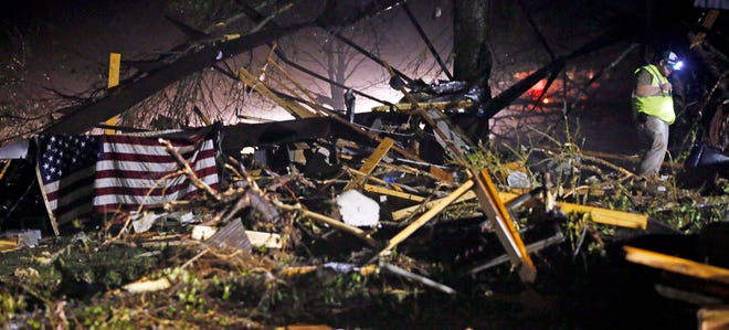 An American flag is mounted on mobile home debris as a searcher looks through the remains of several mobile homes in Louisville, Miss., early Tuesday morning, April 29, 2014 after a tornado hit the east Mississippi community Monday.
