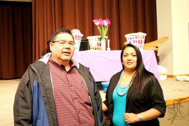 Leander “Russ” McDonald, Spirit Lake tribal chairmen and Mellissa Merrick-Brady, director of Spirit Lake Victim Assistance, stand in front of gift baskets put together by community members in honor of the three children whose lives were tragically taken last year. A candle burning in the background signifies the light of their young spirits.