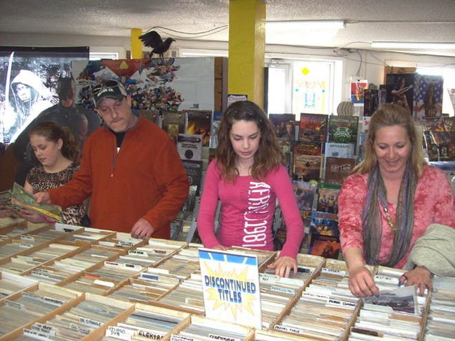 Jason Frappier, second from left, of Herkimer, browses through comic books with daughters, from left, Alexis, 10, and Gabriella, 12, and his fiancée, Kelly Carter, at Ravenswood Comics in New Hartford on April 18. The store joins other comic shops across the country to celebrate Free Comic Book Day on May 3.
