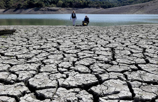 This March 13, 2014 file photo shows cracks in the dry bed of the Stevens Creek Reservoir in Cupertino, Calif.