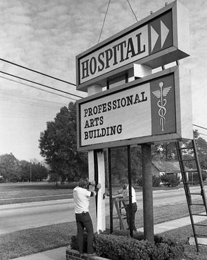 Workers perform maintenance on the Bunnell Hospital sign in this 1981 photo.