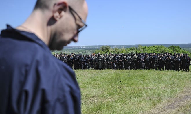 Ukrainian Prime Minister Arseniy Yatsenyuk stands in front of Ukrainian soldiers at a block post on the road at Slovyansk, Ukraine, Wednesday, May 7, 2014. Ukrainian military operations that began Monday to expunge pro-Russia forces from the city of Slovyansk were the interim government’s most ambitious effort so far to quell weeks of unrest in Ukraine’s mainly Russian-speaking east.