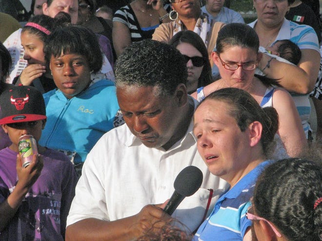 Pastor Harvey Burnett, center left, holds the mother of Trever B. Chick, Tracey Corey, center right, as she addresses the crowd at a prayer vigil for her son Wednesday night. Corey choked back tears as she thanked the crowd of hundreds for attending the vigil in honor of her son who lethally collided with a truck Monday.