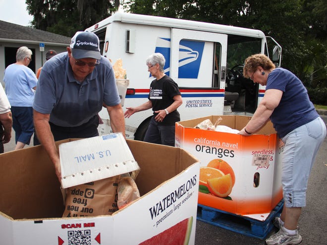 Volunteers from Interfaith Emergency Services and several local churches work to unload food collected by postal carriers in this May 11, 2013 file photo.