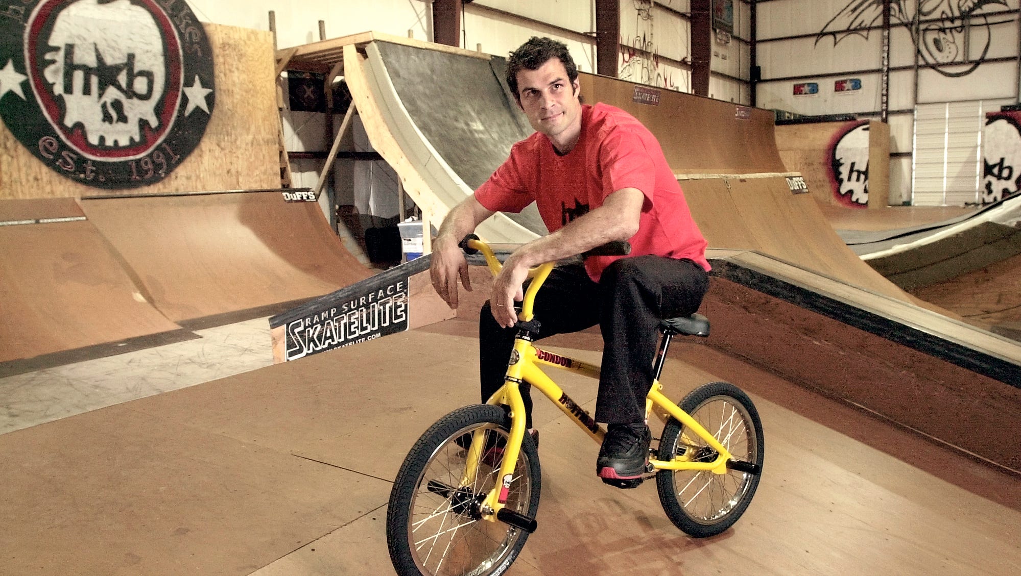 Mat Hoffman Sitting on a Yellow BMX Bike at his Indoor Park