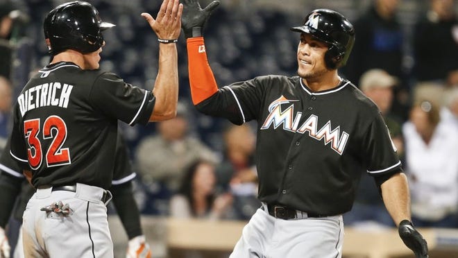 Miami Marlins’ Giancarlo Stanton high-fives with Derek Dietrich after Stanton’s two-run homer in the 11th inning against the San Diego Padres on Thursday night. The homer provided the crucial runs in a 3-1 victory. (AP Photo/Lenny Ignelzi)
