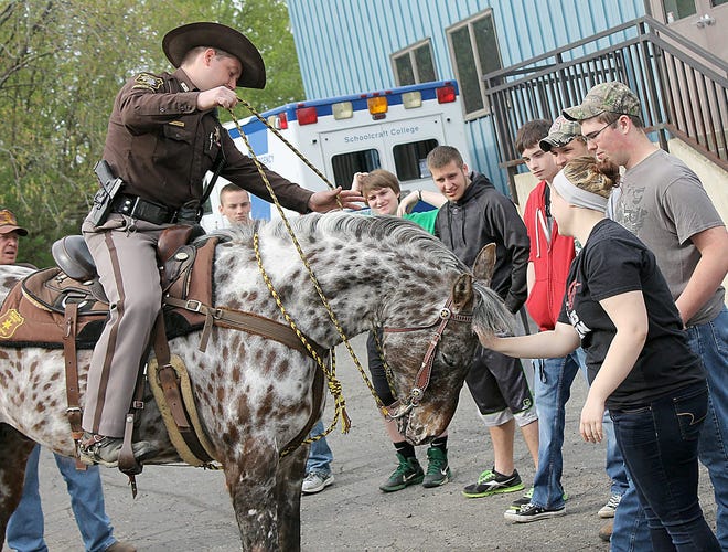 Hillsdale County Mounted Division Officer Tracy Peter allows Savannah Young to pet the head of his horse after a demonstration Friday morning at the Hillsdale ISD Tech Center. Young is a senior at Jonesville High School and part of the tech center's public safety class. ANDY BARRAND PHOTO