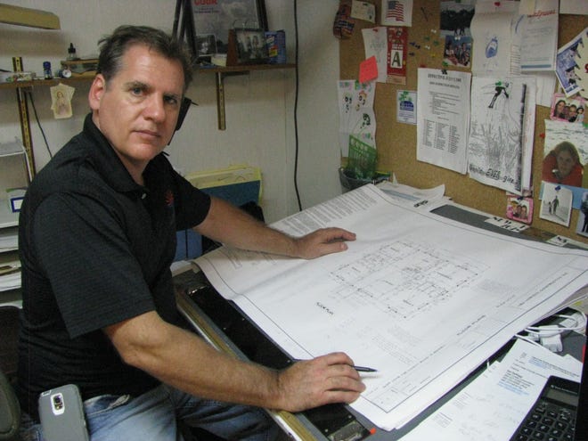 John Junco, owner of New Horizon Construction Inc., looks over building plans at his Port Orange home office.