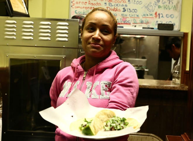 Ines De La Rosa, co-owner of Taqueria La Raza, displays her tacos at the restaurant.