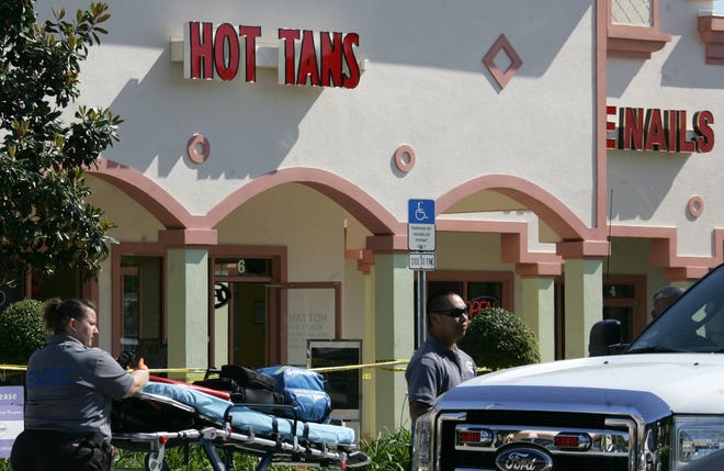 Rescue workers stand by in front of Hot Tans after police shot and killed rape suspect Cheyne Pinkney at the South Daytona business May 6.