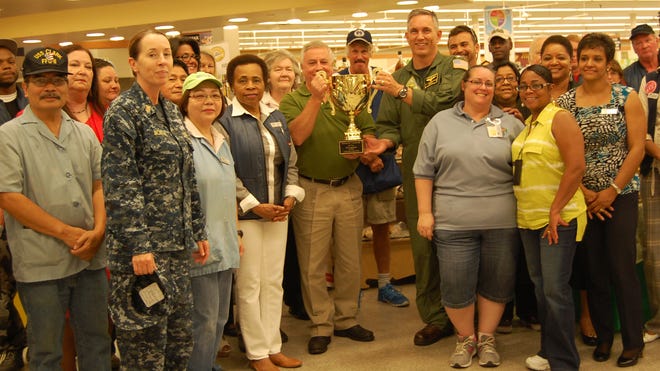 NAS Jax Commanding Officer Capt. Roy Undersander, (center, right) presents the second place trophy of the Director's Award in DeCA's "Best Commissary" competition for FY 2013 to Larry Bentley, NAS Jacksonville Commissary store director, and the entire NAS Jax Commissary team.