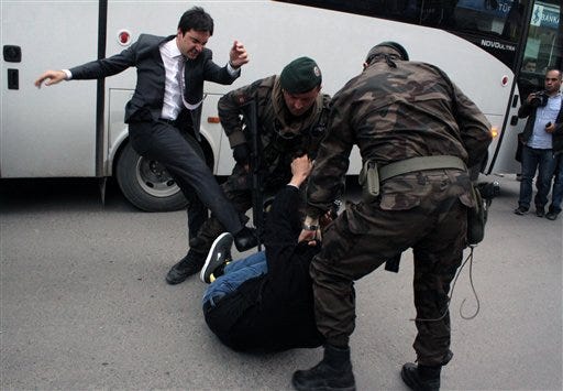In this photo taken Wednesday, May 14, 2014 a person identified by Turkish media as Yusuf Yerkel, advisor to Turkish Prime Minister Recep Tayyip Erdogan, kicks a protester already held by special forces police members during Erdogan's visiting Soma, Turkey. Erdogan was visiting the western Turkish mining town of Soma after Turkey's worst mining accident . AP Photo/Depo Photos)