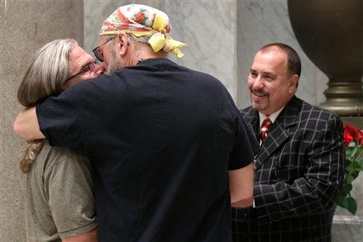 Pastor Randy Eddy-McCain, right, concludes a wedding ceremony at the Pulaski County Courthouse in Little Rock, Ark., for a same-sex couple who did not wish their names used Thursday, May 15, 2014. Marriage licenses were issued to same-sex couples in the county Thursday. (AP Photo/Danny Johnston)
