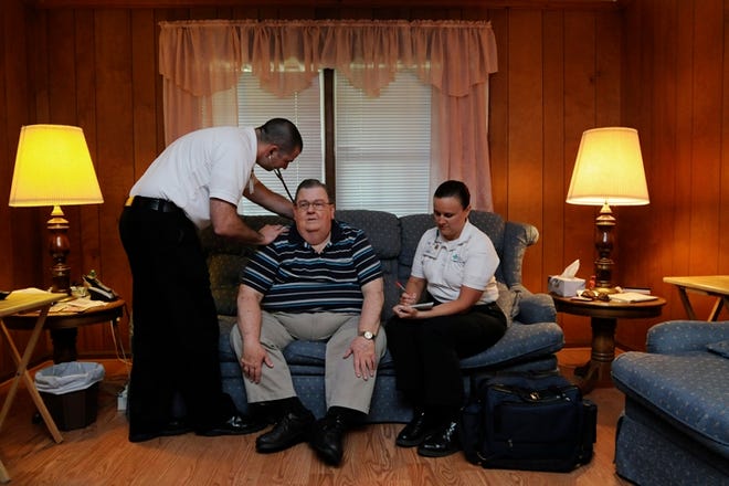 Community paramedics Matt Stevens (left) and Sarah Rivenbark take the vitals on patient Louis Tatum, 70, in the living room of his home in Wilmington on Friday, May 9, 2014.