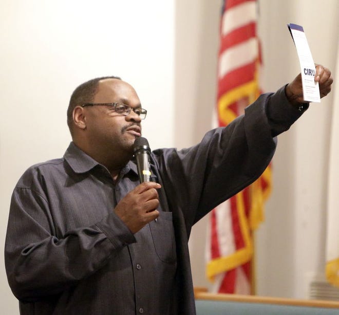 The Rev. Walter S. Moss holds up a CIRV brochure during a recent community meeting. Moss, director of the Stark County Community Initiative to Reduce Violence, is planning a “boots on the ground” campaign to spread awareness of the revitalized organization and its goals.