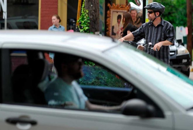 A motorist drives past as bicyclist Jerry Daniel waits to cross Prince Avenue at the crosswalk near Pope Street during the See and Be Seen on Prince Avenue event on Saturday, May 17, 2014, in Athens, Ga. (AJ Reynolds/Staff, @ajreynoldsphoto)