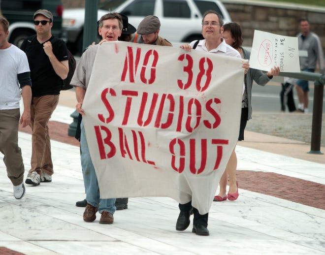 Nick Schmader and Randall Rose, of Occupy Providence, carry a sign showing their displeasure with the 38 Studios loan guarantee as they head to the State House for a protest in May 2013.