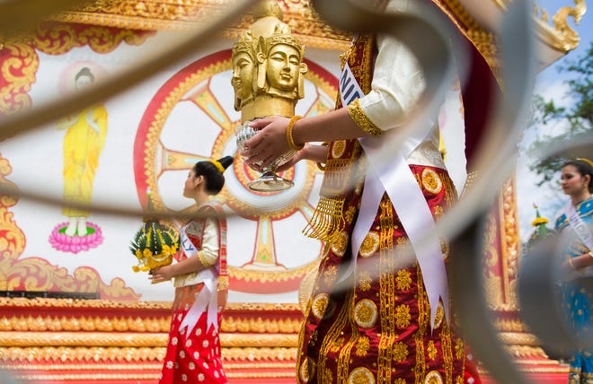 A Miss Lao 2014 contestant holds a Buddhist figure as part of the new-year celebration Saturday, May 17, 2014, at the Lao Buddhist Temple-Wat Phothikaram in Cherry Valley.