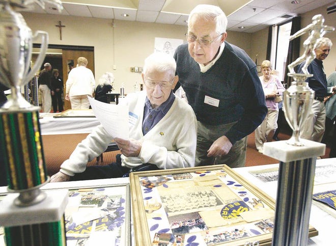 Clem Kracker, 101, left, is accompanied by his son, Jim, while looking over memorabilia Sunday afternoon at the St. Mary's School alumni homecoming and open house. Clem is the oldest living graduate of St. Mary's School.