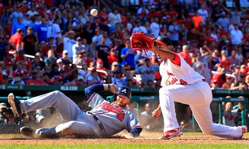 Atlanta Braves' Ryan Doumit, left, scores on a wild pitch by St. Louis Cardinals relief pitcher Carlos Martinez, right, as Martinez covers home during the ninth inning of a baseball game Sunday, May 18, 2014, in St. Louis.