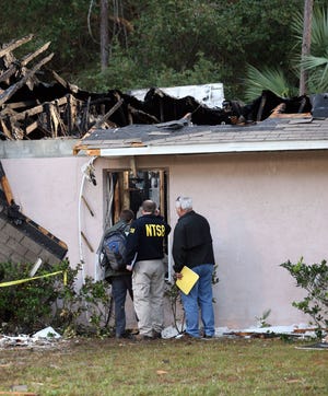 Investigators with the National Transportation Safety Board peer inside a house on Utica Path in Palm Coast on Jan. 5, 2013, after a small airplane crashed into it.