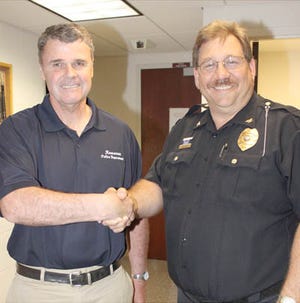 Police Chief Jim Dison, right, congratulates retiring Patrol Officer Chuck Russell, who retired Tuesday.