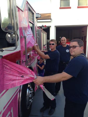 As firefighters get ready for the next cancer awareness campaign, New Smyrna Beach Fire Department crew peel back Engine 51’s pink wrapping that has served as a mobile symbol of communitywide support for the fight against cancer. They are, from right, lieutenants Mike Lynn and Jeff Kromraj, and Driver Engineer Chad Howard.