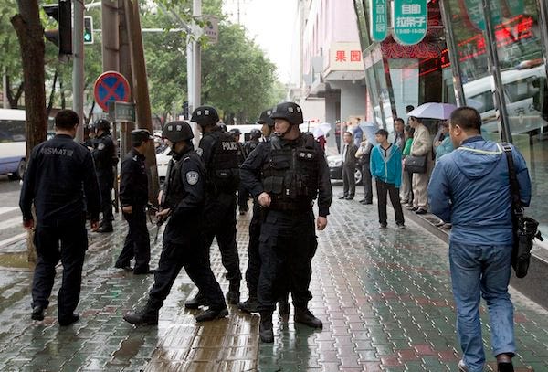 Armed policemen stand guard near the site of the explosion in Urumqi, northwest China's Xinjiang Uygur Autonomous Region Thursday, May 22, 2014. Assailants in two SUVs plowed through shoppers while setting off explosives on a busy street market in China's volatile northwestern region of Xinjiang on Thursday, the local officials said, killing 31 people and injuring more than 90. THE ASSOCIATED PRESS