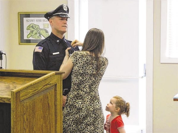 Jim Marot/Special to Advocate
Sgt. Keith Ashley's wife, Rebecca, pins his badge on at Acushnet Town Hall May 12 as his daughter, Lorelai, looks on.