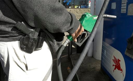 In a photo from April 9, 2014, Greg Champion wears a gun while pumping gas in Detroit. To avoid becoming a carjacking victim, Champion wears a handgun on his hip whenever he's pumping gas. Through May 19, Detroit has recorded 191 carjackings in 2014. (AP Photo/Carlos Osorio)