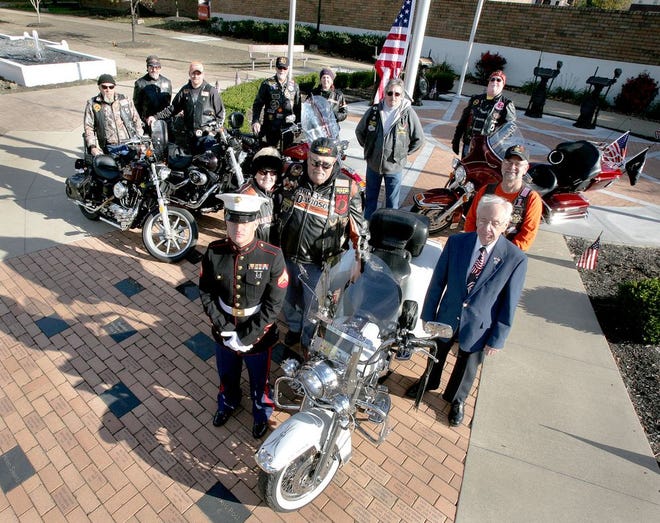 A few members of American Legion Riders from Massillon Post 221 join as an American flag that was flown in Afghanistan and was brought back from Marine Cpl. Daniel Heitger's tour of duty in that country, is raised at the Medal of Honor Memorial in Massillon.