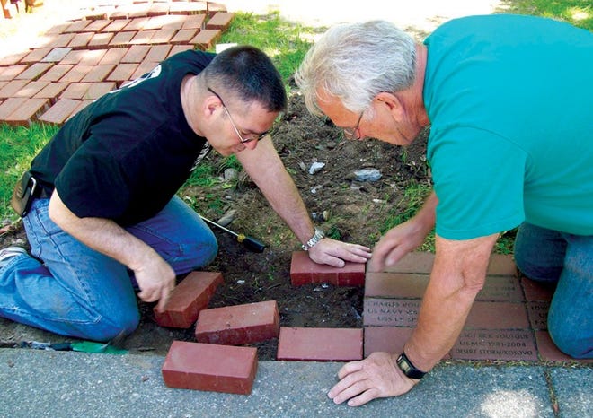 Veteran’s Agent Rick Voutour and volunteer Ralph Sacramone work to install some new memorial bricks at Carter Park for a dedication for Memo- rial Day.