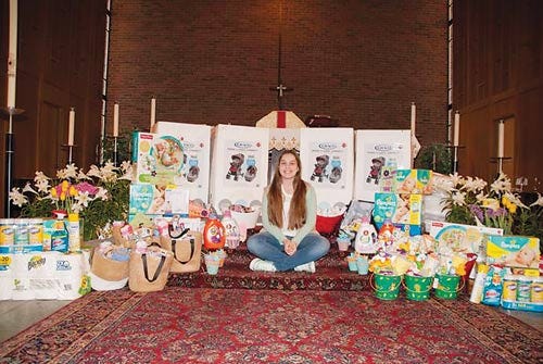 Hannah Aroune sits on the altar of St. Mary’s Episcopal Church of Sparta, with some of the items she collected for Birth Haven of Newton.