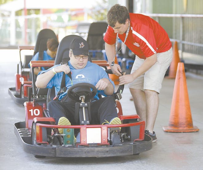 Joe Longo, a summer employee for Sluggers and Putters in Canal Fulton and an Ohio University student, helps Herbie Stanley Jr. get into the seat belt of a go-cart Thursday afternoon. The park owner says he has hired more summer help this season due to improving business.