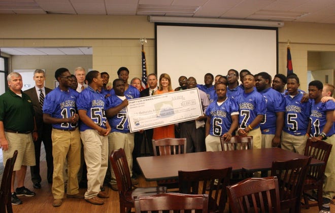 Stuart and Mary Brooke Sligh present a check donation to members of Bethesda Academy's Blazer football team in honor of their son Stu, an honor roll student and star quarterback at Savannah Country Day who died tragically at the age of 16 in 2012 from injuries sustained in a car accident.