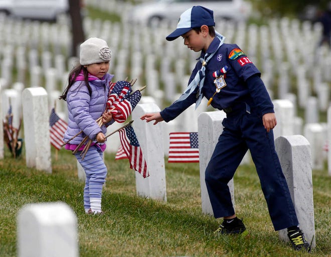 Brooke Radulovich, 4, carries flags for her brother Matthew, 7, a member of Troop 133 at the Golden Gate National Cemetery in San Bruno, Calif.