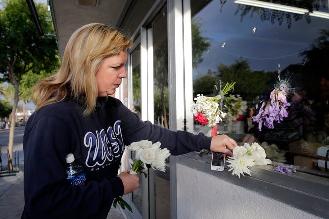 Jennifer Peake places flowers by the window of IV Deli Mart, where part of Friday night's mass shooting took place by a drive-by shooter, on Saturday, May 24, 2014, in Isla Vista, Calif. Sheriff's officials say Elliot Rodger, 22, went on a rampage near the University of California, Santa Barbara, stabbing three people to death at his apartment before shooting and killing three more in a crime spree through a nearby neighborhood. THE ASSOCIATED PRESS