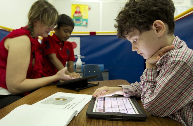 Leo Eichenwald, right, 9, works on his iPad while functional communication teacher Danielle Skala helps Eshan Arefin, 8, work with his iPad at Forest North Elementary School on Thursday May 8, 2014, in Austin, Texas.