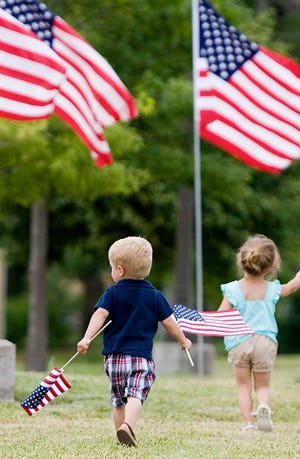 A little boy waves his flags as he leaves the Memorial Day ceremony at Great Overland Station on Monday. About 300 people showed up for the second annual event.