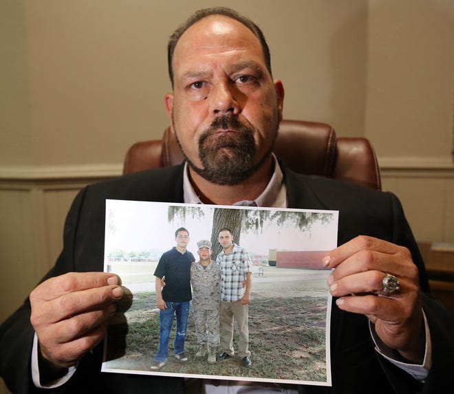 In this file photo, Vincent Salvato holds a family photo of his three sons including Joshua, right, Vincent Jr., left, and Edwin Gonzalez, center, during an interview about Joshua's shooting death at the law offices of Varnell and Warwick in The Villages on Friday, Nov. 30, 2012.