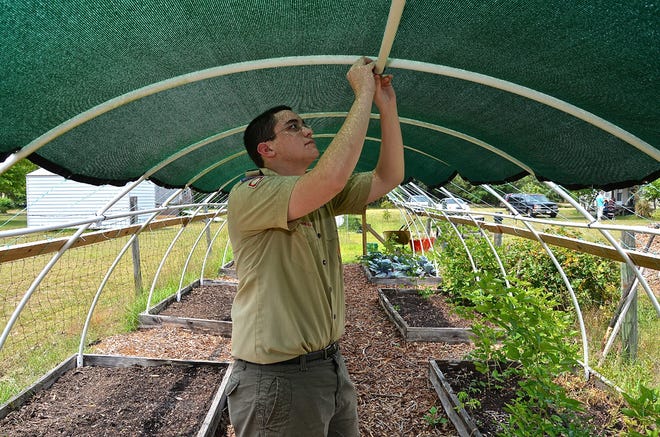 Eagle Scout candidate Alberto Zapata tightens a cable tie on the Hoop House he was building on Saturday at the Feed the Need Garden in Belleview.