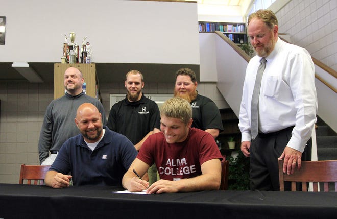 With coaches, school administrators and his father looking on, Havelock’s John Ellis signs to wrestle at Alma College on Friday at Havelock High. The school is located in Michigan. Ellis was a state qualifier the past two seasons.