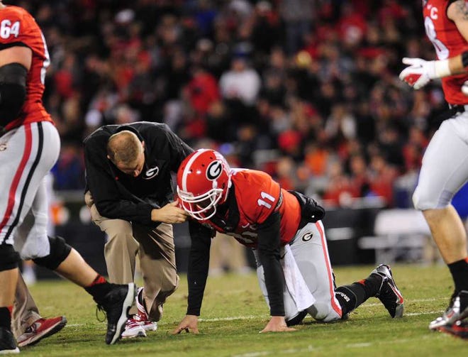 A trainer checks on Georgia quarterback Aaron Murray (11) after being shaken up on a play resulting in an apparent leg injury as Georgia takes on Kentucky at Sanford Stadium on Saturday, Nov. 23, 2013, in Athens, Ga.  (Richard Hamm/Staff) OnlineAthens / Athens Banner-Herald