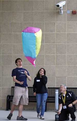 Seniors Kyle Turner, left, and Loanna Oosterdijk, center, launch a hot-air balloon on the last day of school. With them was science teacher Doug Forrest.