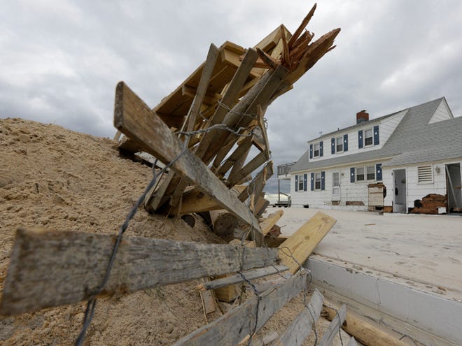 This Nov. 1, 2012, photo shows a pile of sand and debris sitting near a house that was damaged by superstorm Sandy in Brant Beach, N.J. A new psychology study shows that people are wrongly less prone to flee from hurricanes with feminine names. Yet the study finds female named storms have been deadlier in the United States than their macho sounding counterparts.
