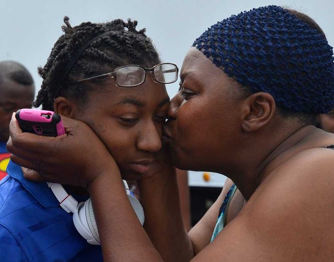 ROTC Cadet Ayzia Armor, left, gets a kiss from Angela Phinazee before leaving to travel to France from Cedar Shoals High School on Tuesday, June 3, 2014. The cadets will march in a parade in Sainte-Mere-Eglise, France on June 6 in remembrance of the 50th anniversary of D-Day.    (Richard Hamm/Staff) OnlineAthens / Athens Banner-Herald